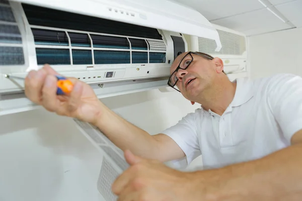 Hispânico reparador de ar condicionado homem realizando manutenção — Fotografia de Stock