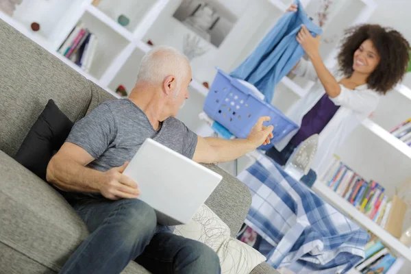 Anciano con mujer joven usando internet en casa —  Fotos de Stock