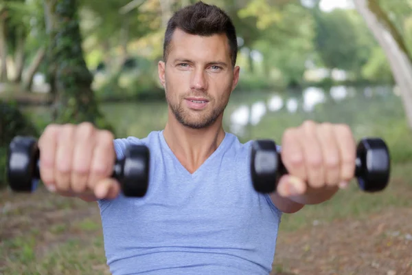 Hombre deportivo haciendo ejercicio con pequeñas mancuernas al aire libre —  Fotos de Stock