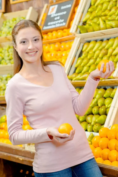 Femme tenant des oranges en magasin — Photo