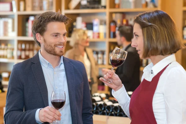 Jovem homem amostragem vinho com comerciante de vinho do sexo feminino — Fotografia de Stock