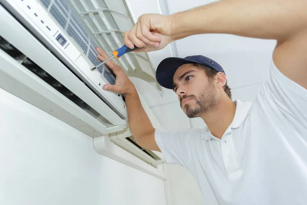 Portret van halverwege volwassen mannelijke technicus reparatie Air Conditioner — Stockfoto