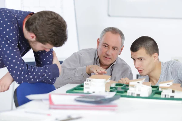 Architetto e studenti in ufficio guardando il modello di casa — Foto Stock