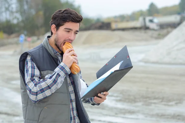 Man on construction site eating sandwich — Stock Photo, Image