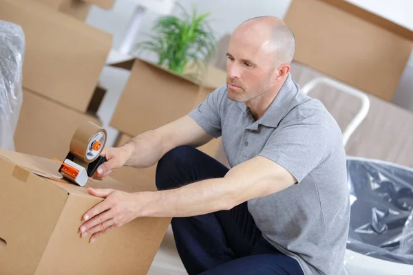 Hombre cerrando cajas para mudarse a un nuevo hogar — Foto de Stock