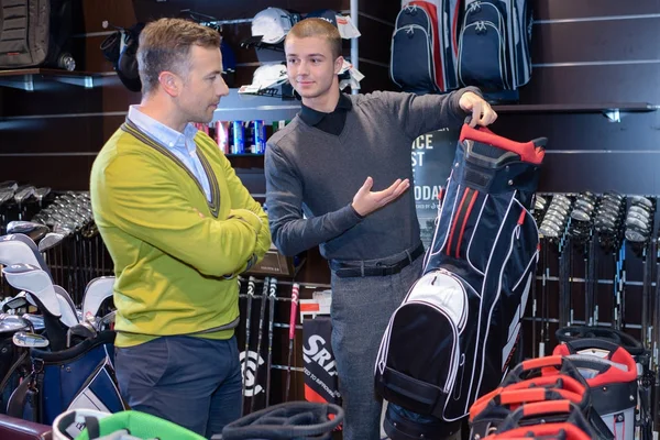 Äldre mannen i golf store talar till shop assistent — Stockfoto