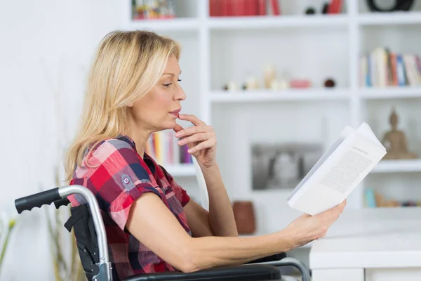 Patientin im Rollstuhl liest zu Hause ein Buch — Stockfoto