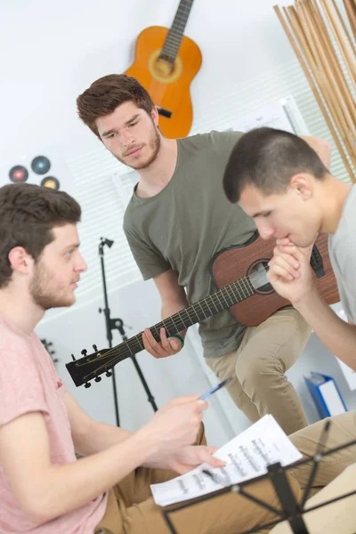 Amigos do sexo masculino tocando guitarra acústica e cantar em casa — Fotografia de Stock