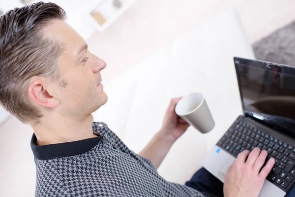 Homem usando um laptop enquanto bebe café — Fotografia de Stock