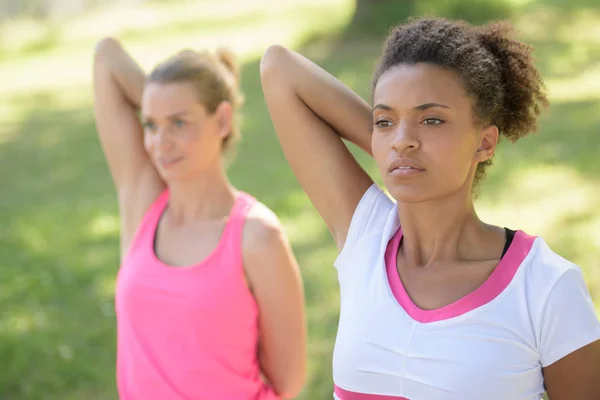 Two girlfriends having arms stretching exerciseq — Stock Photo, Image