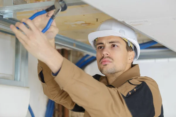 Bel giovane uomo pannello soffitto di fissaggio con pinze — Foto Stock