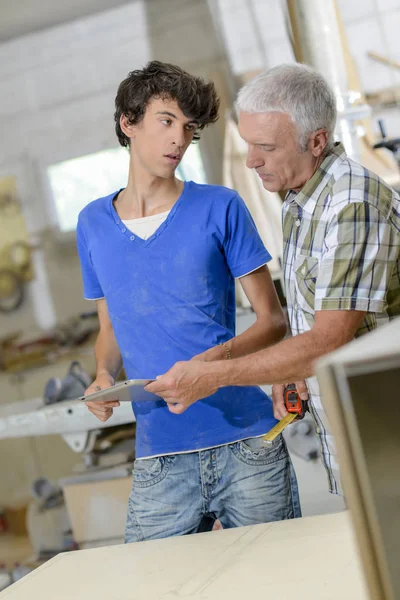 Carpenter with apprentice, looking at tablet — Stock Photo, Image