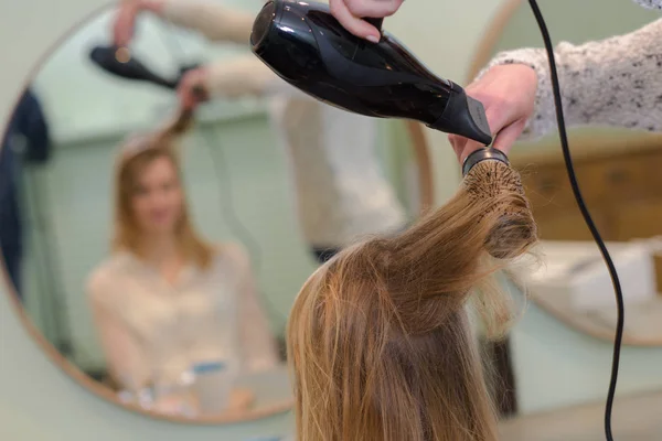 Hairdresser blow drying woman's hair — Stock Photo, Image