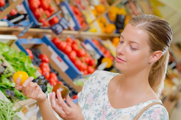 Lady holding one brown and one yellow tomato — Stock Photo, Image