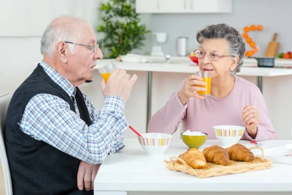 Glückliches Seniorenpaar diskutiert beim Frühstück am Tisch — Stockfoto