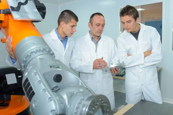 Profesor con estudiantes explicando el equipo robótico —  Fotos de Stock