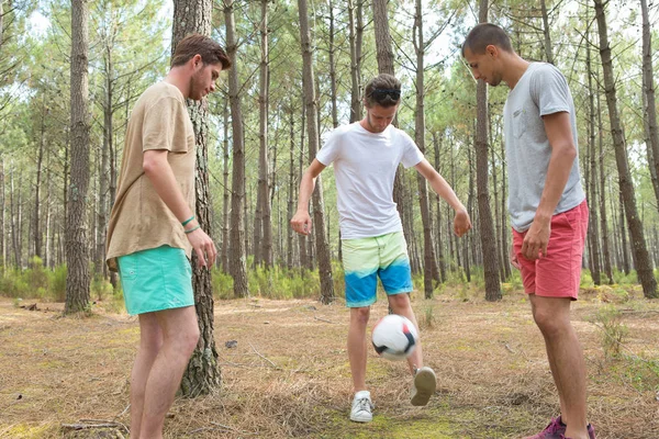 Trzech chłopców gry w piłkę nożną w lesie — Zdjęcie stockowe