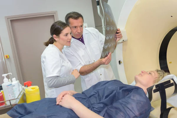 Лікарі перевіряють рентгенівське зображення поруч із пацієнтом — стокове фото