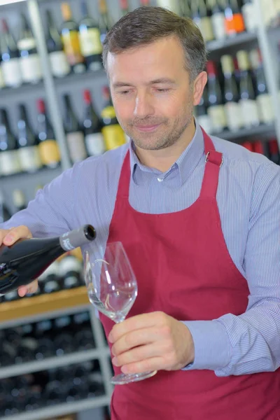 Mannelijke verkoper dragen schort holding glas wijn proeverij — Stockfoto