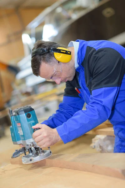 Werknemer schuren van hout voor luxe jachten in bouwwerf — Stockfoto