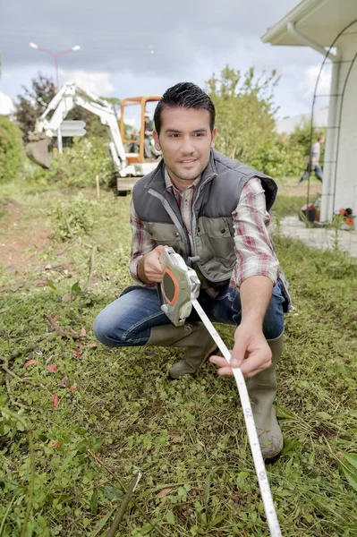 Constructeur à l'aide d'un mètre ruban dans le jardin — Photo