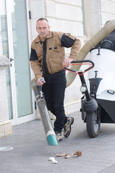 Man met vacuüm op straat schoonmaken voertuig — Stockfoto