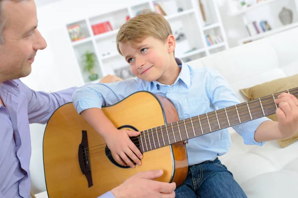 Young boy playing guitar to father — Stock Photo, Image