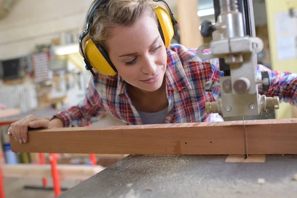 Carpinteiro feminino corte de madeira com um quebra-cabeça elétrico — Fotografia de Stock