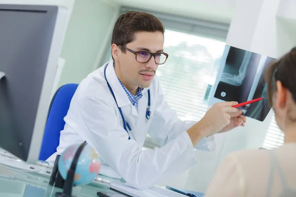 Fisioterapeuta explicando radiografía al paciente en clínica —  Fotos de Stock