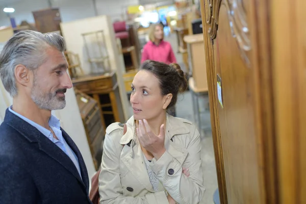 Cliente femenino discutiendo con vendedor masculino en tienda de segunda mano — Foto de Stock