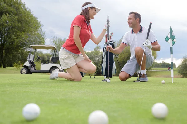 Casal agachado no campo de golfe — Fotografia de Stock