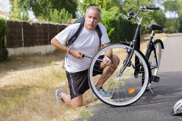 Middle aged man pumping up bicycle tyre — Stock Photo, Image