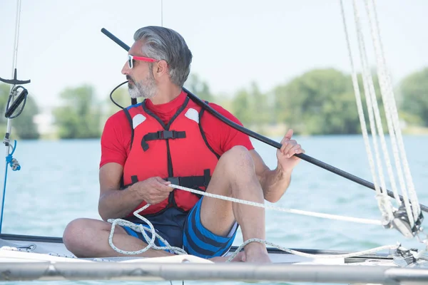 Bello maturo uomo vela su hobby catamarano — Foto Stock