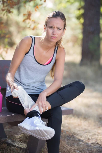 Фитнес женщина страдает болезненным растяжением лодыжки после бега — стоковое фото