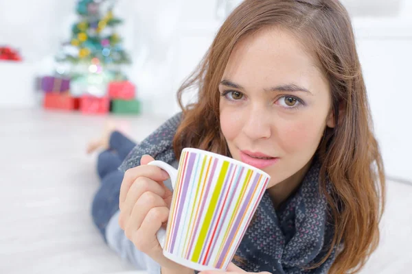 Vrouw liggend op de vloer met een kopje thee — Stockfoto