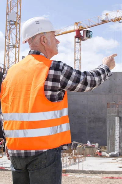 Senior konstruktora w budowlani, wskazując na zewnątrz — Zdjęcie stockowe