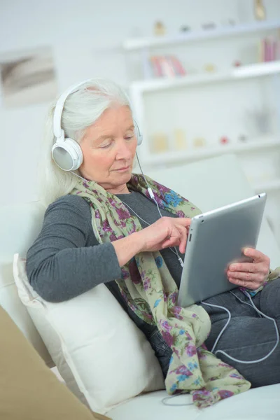 Mormor med surfplatta och bär hörlurar — Stockfoto