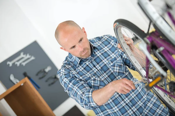 Homme serrage écrou sur vélo dans l'atelier — Photo