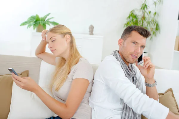 Couple on their cellphones, backs to eachother — Stock Photo, Image