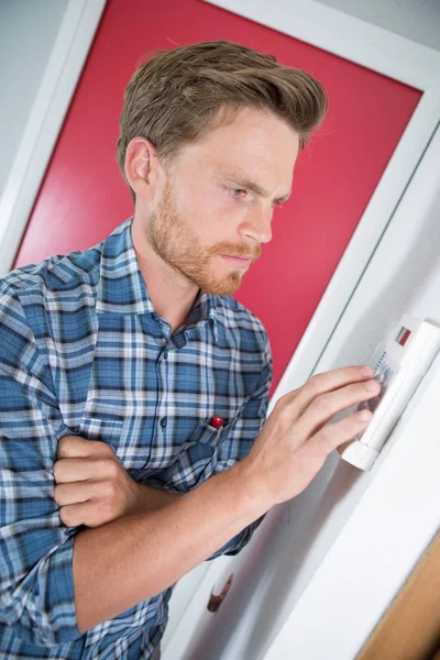 Person stellt Thermostatsteuerung an einer Zentralheizung ein — Stockfoto