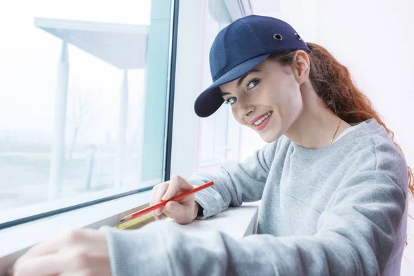 Mujer joven midiendo la pared con cinta métrica — Foto de Stock