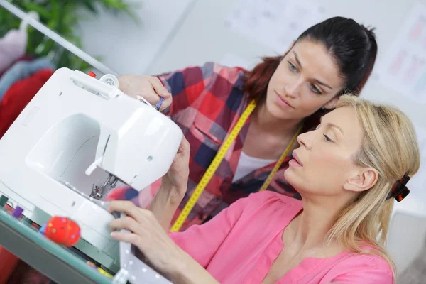 Duas mulheres em torno da máquina de costura — Fotografia de Stock