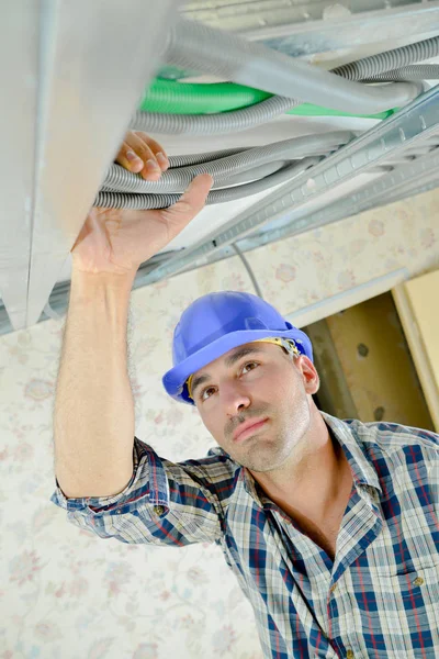 Construtor segurando cabos no nível do teto — Fotografia de Stock