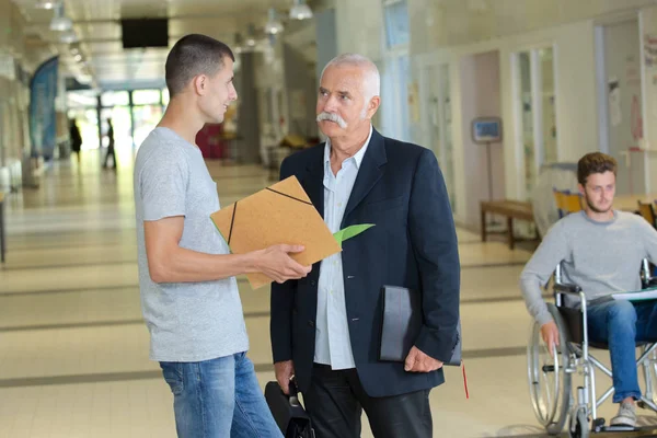 Gymnasielärare som pratar med manlig student utanför klassrummet — Stockfoto