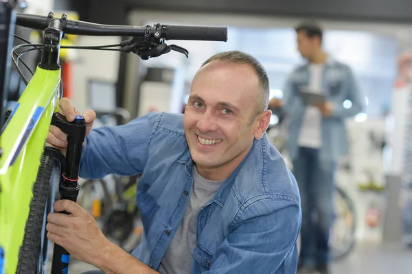 Чоловік перевіряє велосипед перед покупкою в спортивному магазині — стокове фото