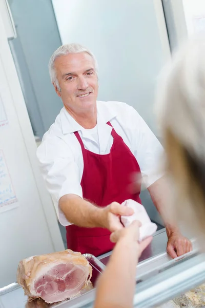 Butcher passing produce to customer — Stock Photo, Image