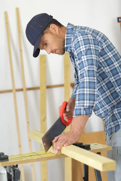 Mann sägt Holz mit der Handsäge — Stockfoto