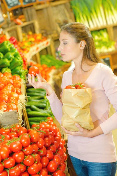 Pani trzyma worek papierowy, wybierając pomidory — Zdjęcie stockowe