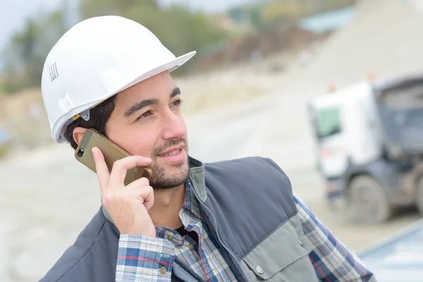 Mannen på mobiltelefon på byggarbetsplats — Stockfoto