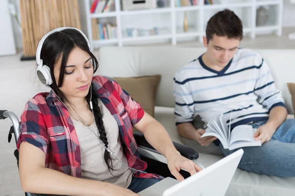 Vrouw in rolstoel met behulp van een computer terwijl vriend leest — Stockfoto